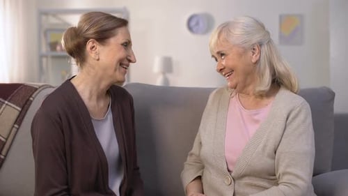 Two Smiling Senior Women Talking and Hugging