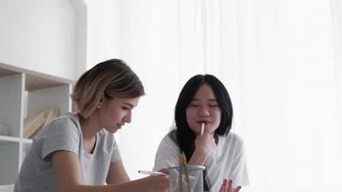 Collaborating Young Women Writing in Notebooks Indoors