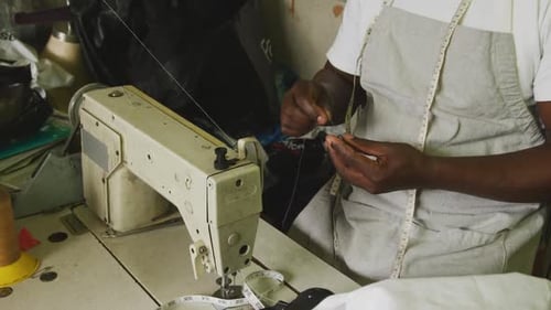 Afrikanischer Mann bereitet den Faden zum Nähen vor