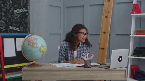 Enthusiastic Teacher Communicates on Laptop in Classroom