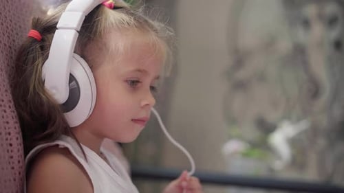 Girl Listens to Music on Headphones Indoors