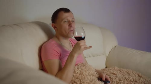 Man Relaxes with Wine Watching Television at Home