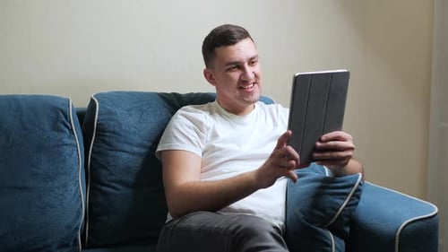 Man on Couch Video Calling on Tablet Device