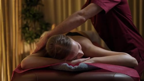 Spa-Behandlungen Professioneller Masseur macht eine entspannende Rückenmassage zu einer jungen weiblichen schönen Frau