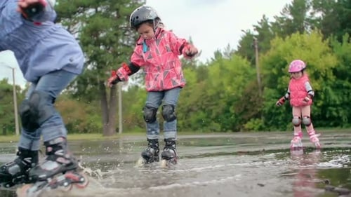Children Roller Skating Together Through Puddles in a Park