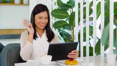 Asian Woman Having Video Call on Tablet Pc at Cafe