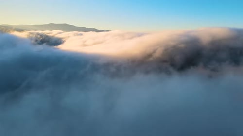Aerial View of Landscape Above Foggy Fast Moving Clouds Covering Mountain Hills at Sunset