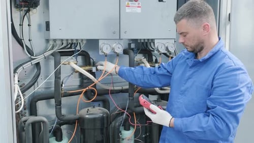 Engineer Inspecting Electrical Machinery with Voltage Meter
