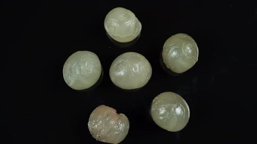 Peeled Longan Fruits on Black Surface