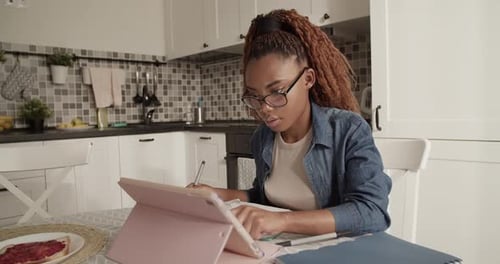 Woman Studies with Tablet at Kitchen Table