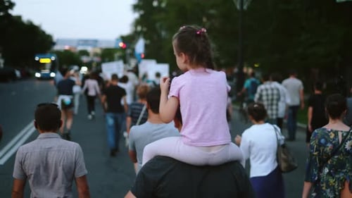 Crowd Walking on City Street with Child on Shoulders