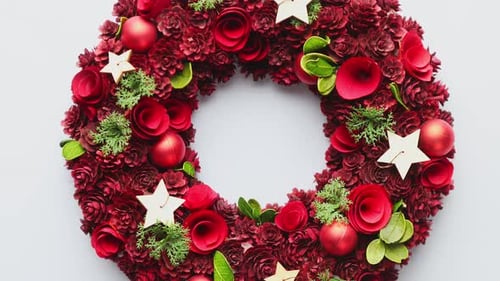 Top View of a Large Christmas Wreath Made with Red Ornaments Placed on White Plain Background