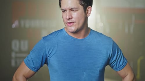 Close-up shot of Caucasian young male athlete or sportsman standing in the dark of gym club stadium.