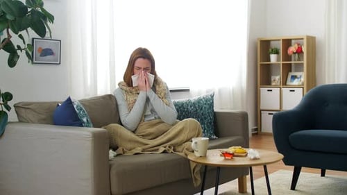 Woman on Couch Blowing Her Nose