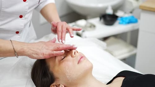 Cosmetologist Applies Facial Moisturizer to Patient