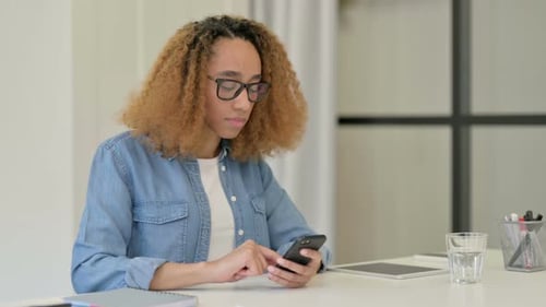 Young Woman Using Smartphone at Desk Indoors