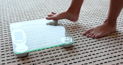 Weibliche Gewichtsmessung auf Gesundheitswaage