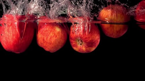 Row of Red Apples Splashing Into Clear Water
