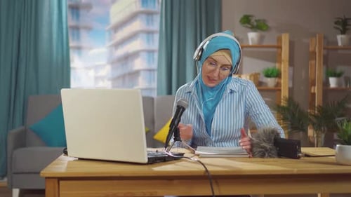 Woman with Headscarf Speaking into Microphone at Desk