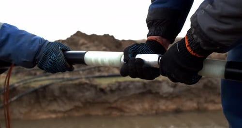Workers connecting heavy cable in rural setting