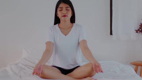 Woman Meditating on Bed Indoors