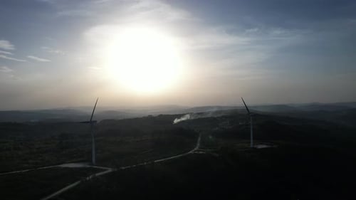 Wind Turbines Rotating Over Rolling Hills at Sunset