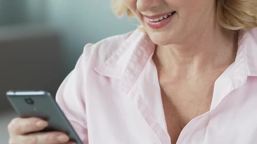 Pretty Middle-Aged Female Viewing Children's Photos on Smartphone, Close-Up