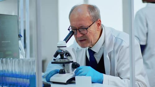 Senior Scientist Using Microscope in Bright Laboratory