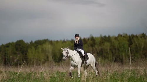 Woman Rides White Horse in Grassy Rural Field