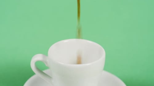 Coffee Pouring into White Cup on Green Background