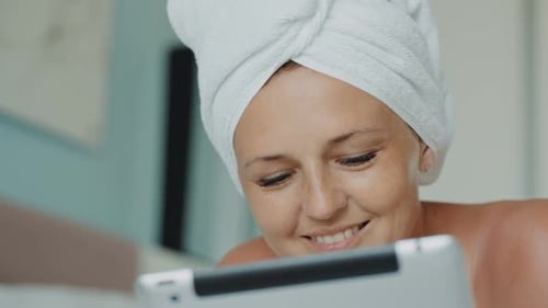 Woman with Towel Looking at Tablet Device