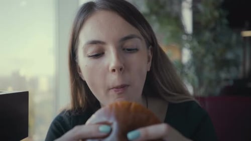Footage Young Woman Eating Tasty Burger in Fast Food Restaurant