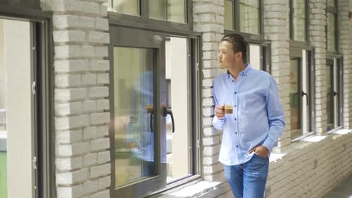 Young Man Drinking Coffee by City Building