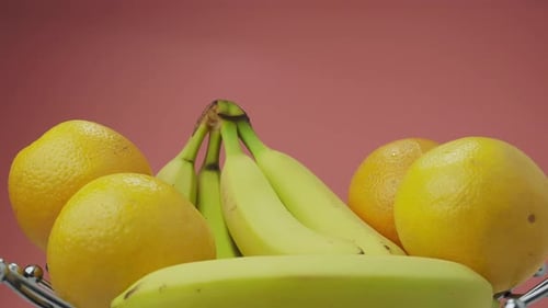 Bananen und Orangen auf rosafarbenem Hintergrund