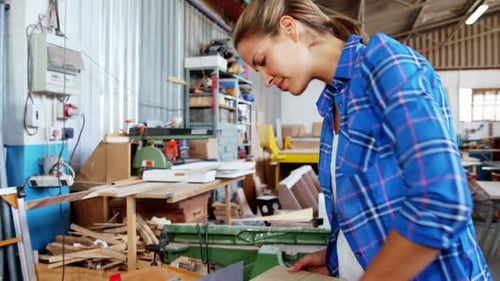 Woman Inspects Wood in Workshop, Smiles