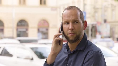 Ein kaukasischer Mann spricht auf einem Smartphone in einem Stadtgebiet Nahaufnahme einer bunten Straße