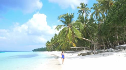 Slow motion: woman sunbathing walking on white sand beach turquoise water