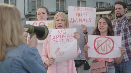 Une foule de personnes défendant les droits des animaux dans une ville urbaine avec une femme floue criant à travers un mégaphone