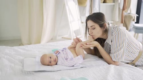 Mother Interacting With Baby on Bed in Home