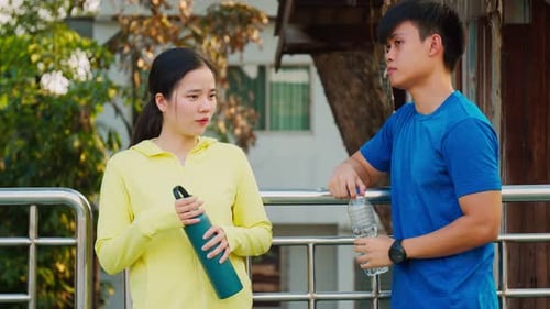 Young Man and Woman Drink Water After Exercise