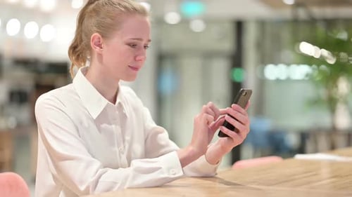 Smiling Woman Using Smartphone at Work Indoors