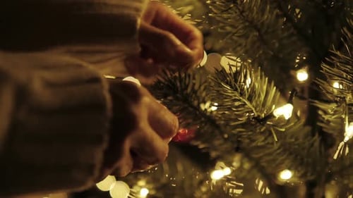 Hands Decorating Christmas Tree with Round Ornament