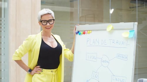 Confident Woman Presents Plan on Whiteboard in Office