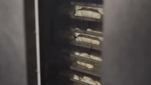 Process of Baking Tasty Croissants on Racks in Rotating Oven in a Bakery