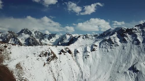 Montanhas enormes cobertas de neve. Panorama dos picos das montanhas, céu azul com nuvens brancas