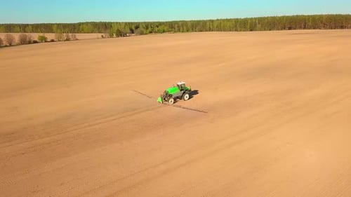 Tractor Spraying a Field with Sprayer Herbicides and Pesticides at Sunset