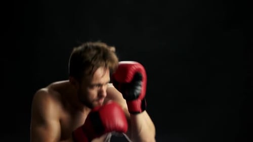 Shirtless Man Boxing with Red Gloves on Black