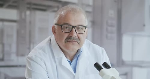 Scientist Smiling Next to Microscope in Bright Laboratory