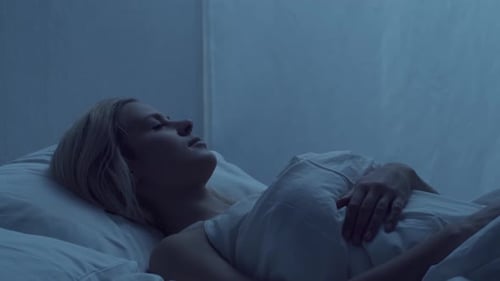 Young woman lying in the bed at night. Beautiful sleeping girl. Twilight in the bedroom.