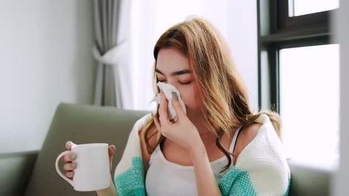 Young Woman Blowing Nose While Drinking
